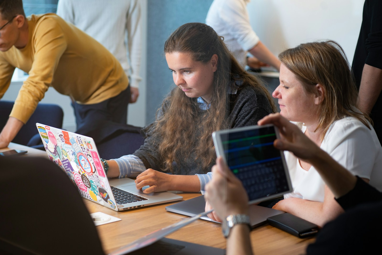 a group of people sitting around a table with laptops